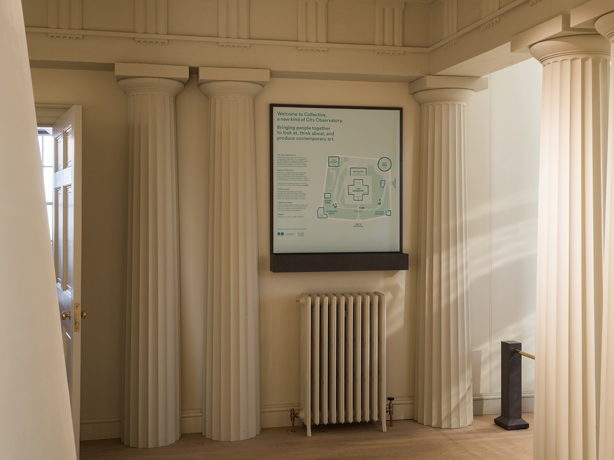 A room with columns lining the walls. A large map of the Collective site hangs on the wall.