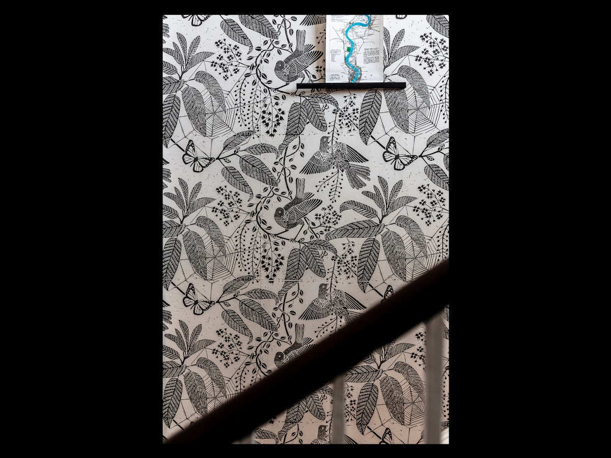 A black and white wallpaper with botanical print. There are birds and butterflies interspersed within.