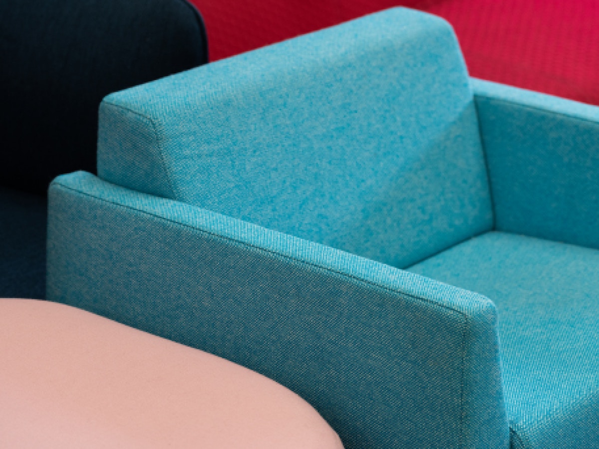 A blue armchair. There is a pink piece of furniture to its left.
