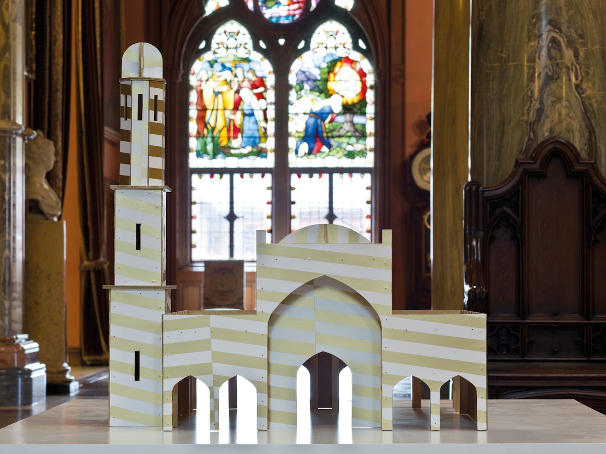 A small model of church in front of a stained glass window.