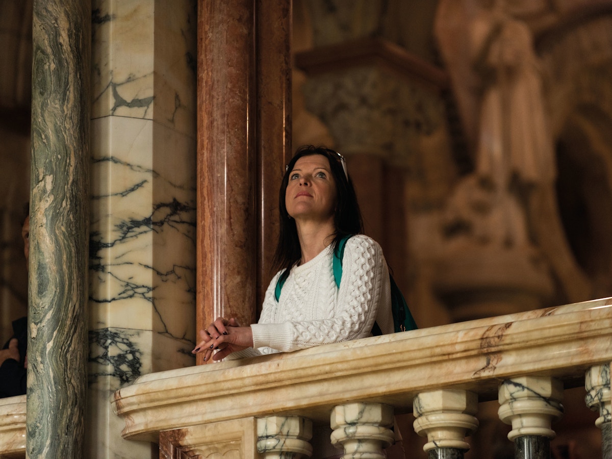 Lady standing at a balcony in a marble church.