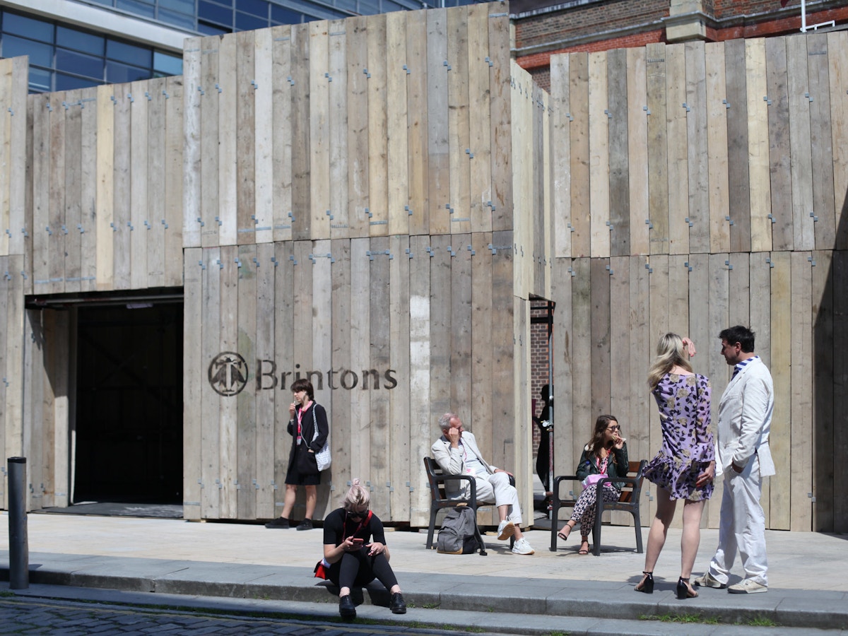 People standing outside of a wooden structure in the sunshine.