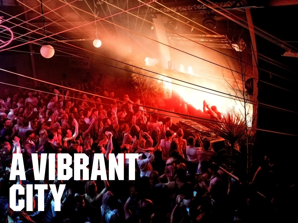Text that reads "A vibrant city" in white sitting onto of a background of a crowd at a concert.