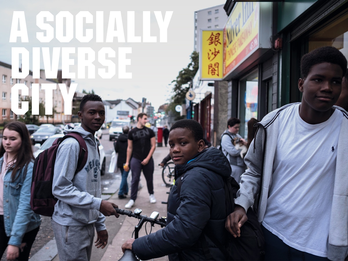 Text that reads "a socially diverse city" on a background of three boys staring at the camera with other people in the background.
