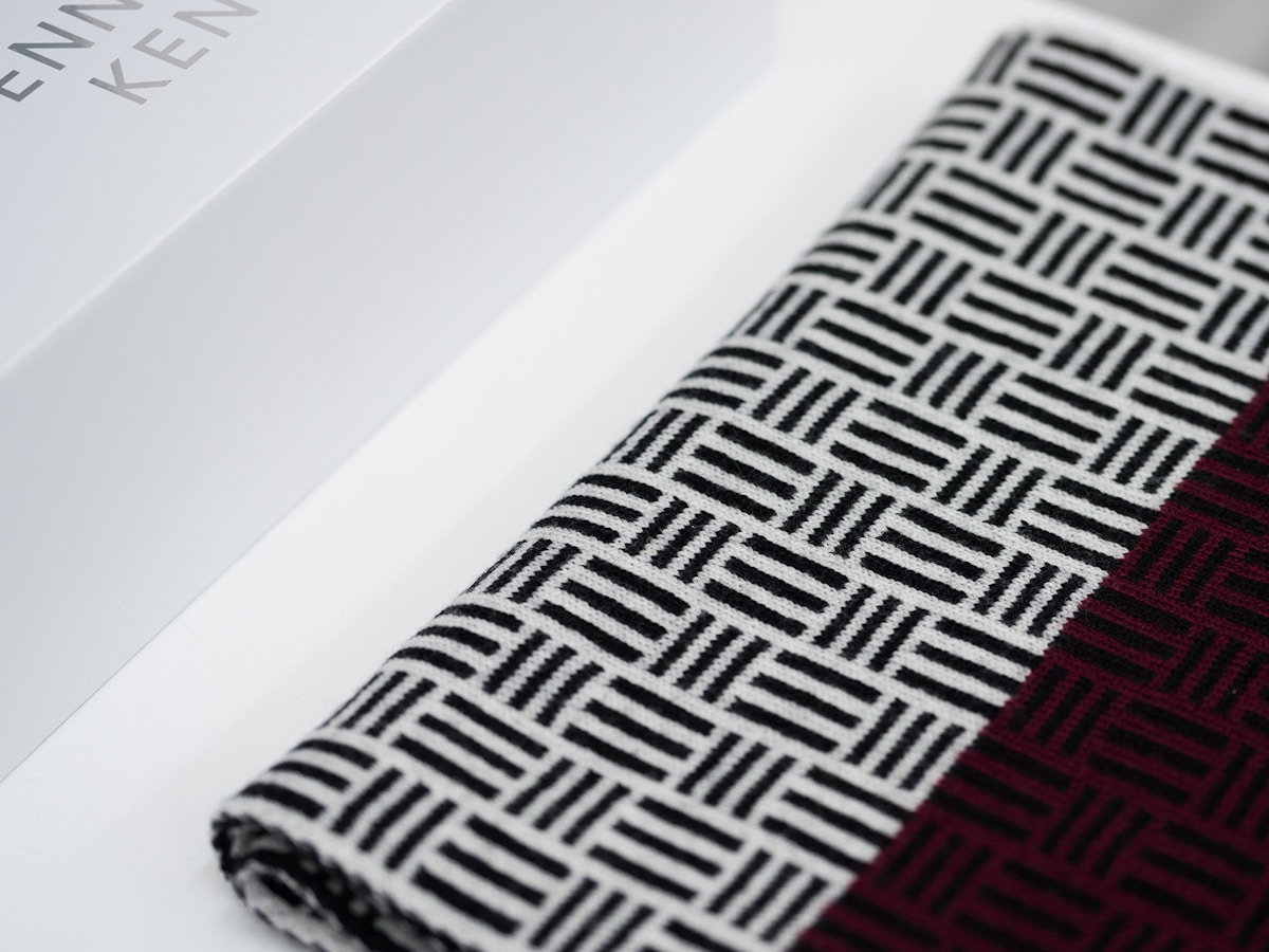 A black and white dash pattern on a scarf that sits next to a white box.