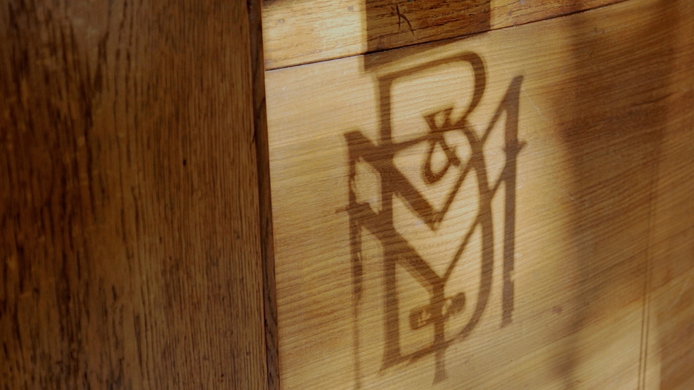 A shadow of the original MYB logo on a piece of wood.