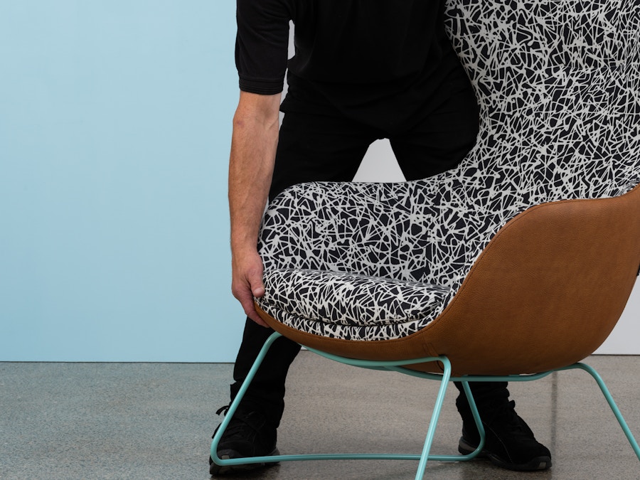 A man dressed in black lifting an armchair.